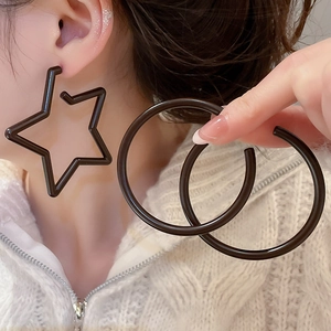 Close-up of black acrylic star earring and circular hoops worn by a model