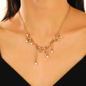 Detail view of a gold-tone bow necklace with white pearls on a model's neck
