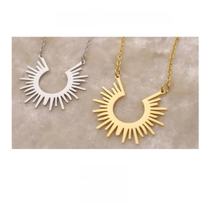 Detail of minimalist sunburst pendant necklaces in gold and silver finish on soft fabric
