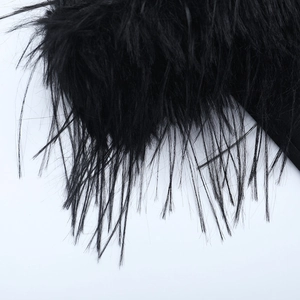 Détail des plumes d'autruche noires et du tissu texturé sur la robe de soirée