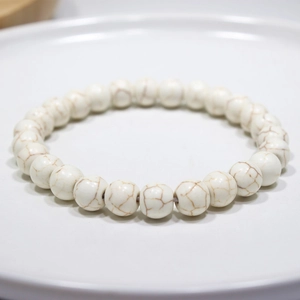 Detailed macro shot of white howlite beaded bracelet with natural marble texture on tray
