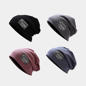 Détail de quatre bonnets en noir, gris, bordeaux et bleu avec des patchs lettrés stylés