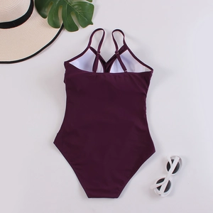 Deep purple one-piece swimsuit with cross-back straps and summer holiday accessories