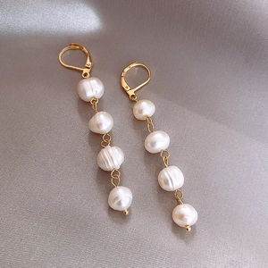 Detailed view of gold drop earrings with four irregular baroque pearls on silk