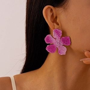 Close-up of oversized pink gradient crystal flower earrings worn by a female model