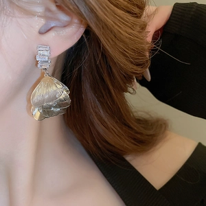 Close-up of model wearing silver petal drop earrings with clear rectangular zircon stones