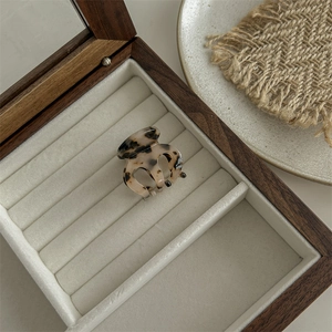 Detailed view of leopard print acetate hair claw clip on beige velvet in a wooden box