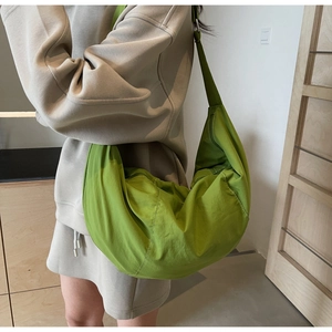 Side view of large green nylon dumpling crossbody bag worn by model for casual style