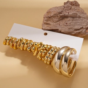 Minimalist gold flower and star C-shaped earring set displayed on white card with rock