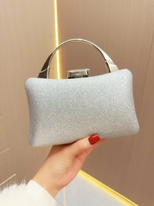 Detail of silver glitter evening clutch with round metal handle held by hand