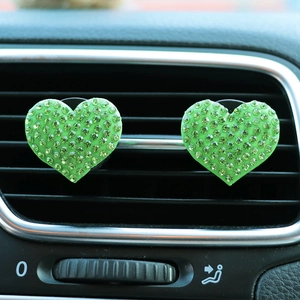 Close-up of heart-shaped green rhinestone vent clips on car air conditioning grille