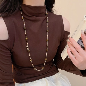 Detail der Vintage Tigerauge- und Perlenkette an einem Model mit feinen Metallkettengliedern