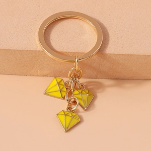Detail of yellow enamel diamond-shaped charms on golden keychain with luxury background