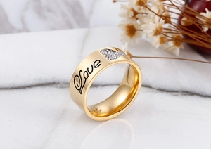 Macro detail of gold-plated wide ring with Love engraving and heart zirconia inlay