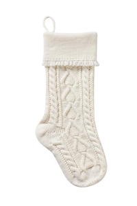 Close-up of cream knit Christmas stocking with woven heart pattern and tassel detail