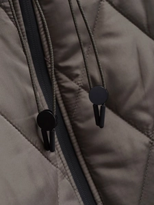 Detailed close-up of olive green quilted jacket featuring a drawstring toggle and zip