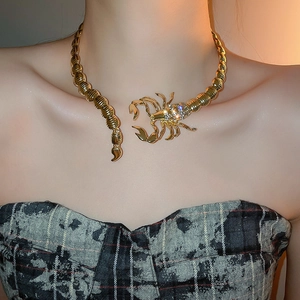 Detail of gold scorpion choker necklace with rhinestones worn by a model in close-up