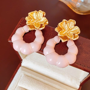 Détail macro de boucles d'oreilles fleur dorée vintage avec pendentifs en C rose nervuré