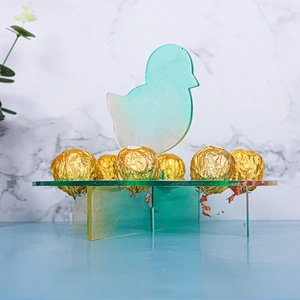 Detail of chick-shaped acrylic dessert stand with chocolate balls on marble surface