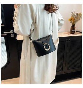Detail of a vintage black bucket bag showing the large golden U-shaped metal buckle on the leather