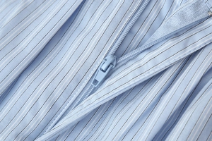 Macro shot of invisible zipper detail on light blue striped fabric shirt set