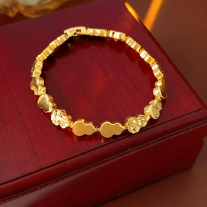 Close-up of golden heart-shaped link bracelet with textured and polished finishes