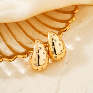 Detailed close-up of gold teardrop earrings with shimmering cubic zirconia stones