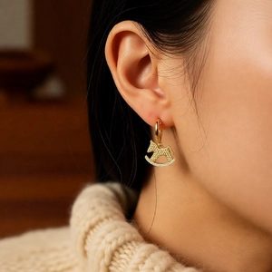 Détail de boucles d'oreilles cheval à bascule plaquées or 18k avec zircon sur un modèle