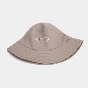 Détail de la broderie 1% sur un bob en coton beige avec des coutures soignées