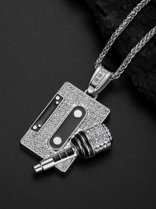 Close-up of silver hip hop pendant with rhinestones microphone and cassette tape design