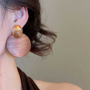Detail view of retro geometric wooden drop earring on model with amber resin element