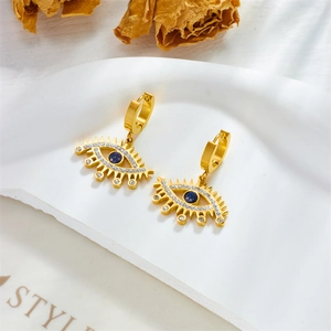 Gold-plated evil eye hoop earrings with blue and white zircons on a white ceramic tray