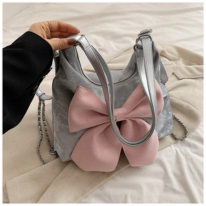 Close-up of a grey handbag featuring a large pink bow and elegant silver chain straps
