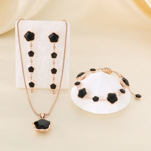 Detail of elegant gold jewelry set with black flower necklace, earrings and bracelet
