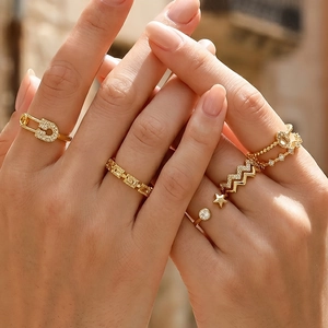 Detail of 18K gold plated zircon rings featuring safety pin and star charms style