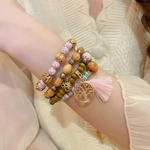 Close-up of bohemian multilayer sandalwood beaded bracelet with tree of life charm and tassel