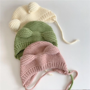 Detail of plush baby beanies with bear ears in cream, green, and pink colors
