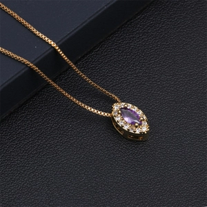 Detail of gold box chain necklace featuring a purple teardrop zircon pendant