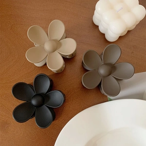 Matte flower hair claws in beige, brown and black set on a rustic wooden surface