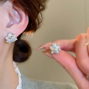 Close-up of star-shaped pearl stud earring with gold accents and sparkling rhinestones