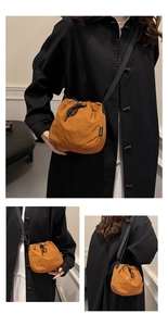 Detail view of pumpkin orange drawstring bucket bag with adjustable black shoulder strap