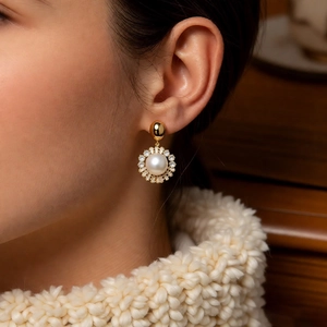 Detail of pearl sunburst earrings with gold plating and zircons worn on model ear