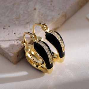Macro shot of French vintage gold hoops with black enamel and white zircon details