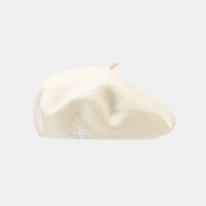 Gros plan détaillé du béret en laine crème avec une élégante broderie blanche