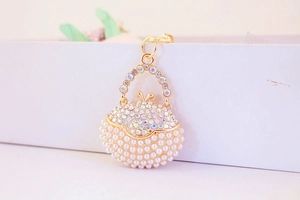 Detail of gold handbag keychain with iridescent rhinestones and white pearls