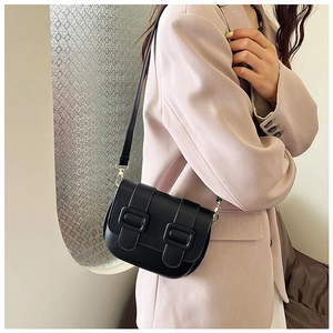 British style black saddle bag with double buckles worn over a pink blazer for women