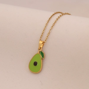 Collana in acciaio al titanio dorato con ciondolo a forma di avocado verde su tessuto beige