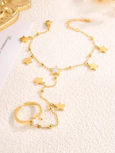 Macro detail of a gold star ring-bracelet set with white shell inlay on textured surface