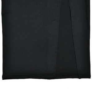 Détail de l'ourlet de robe noire montrant la texture du tissu et la fente latérale