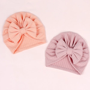 Close-up of ribbed texture and oversized bows on soft pink newborn beanies